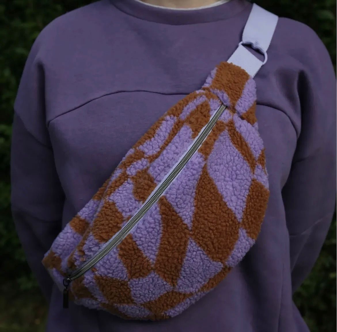 Umhängetasche aus Teddystoff in Flieder und Rostrot über einem lila Pullover