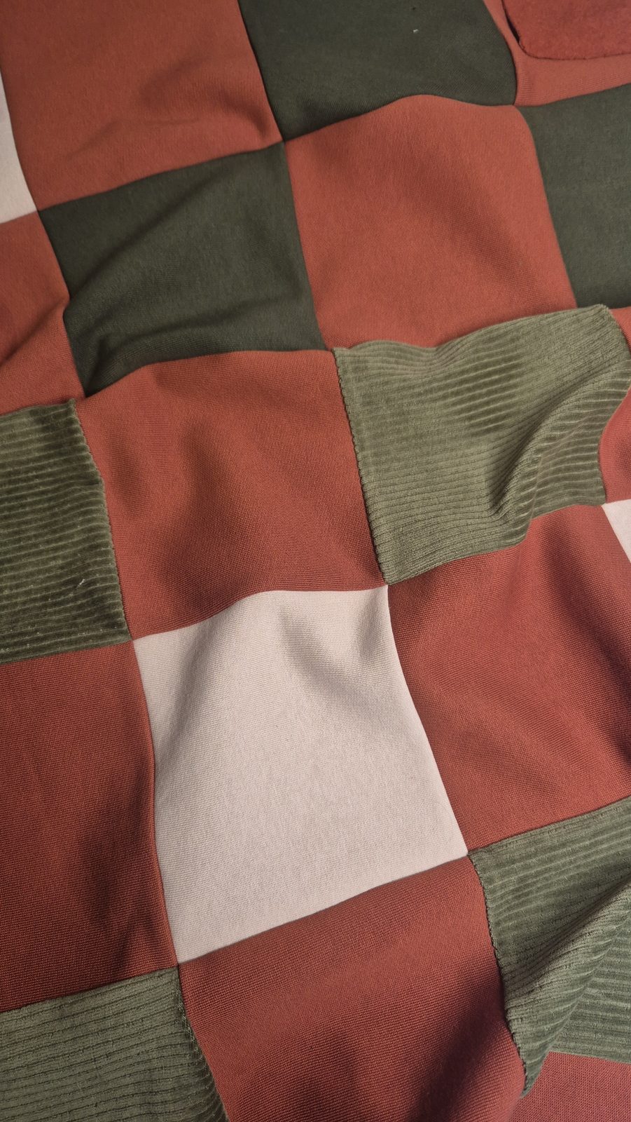 Nahaufnahme von Patchwork-Quadraten in Rostrot, Creme und Oliv