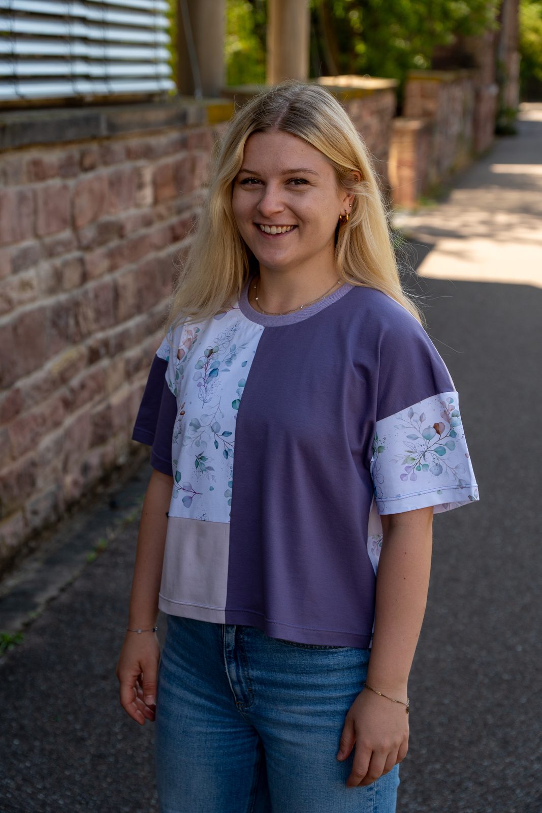 Rita in Violett und Blumendruck in einer Backsteingasse