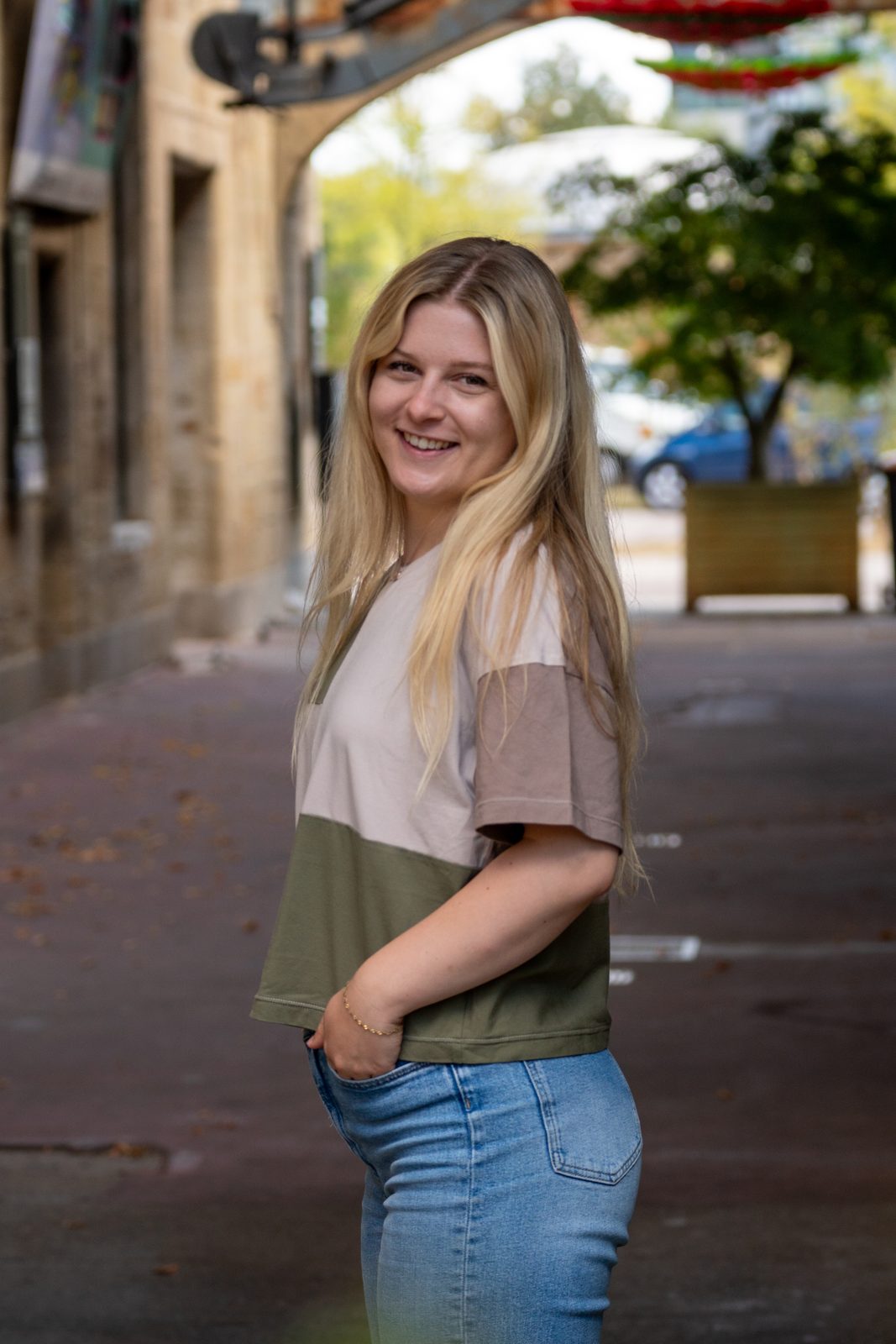 Rita in Taupe und Oliv, auf einer Kopfsteinpflasterstraße