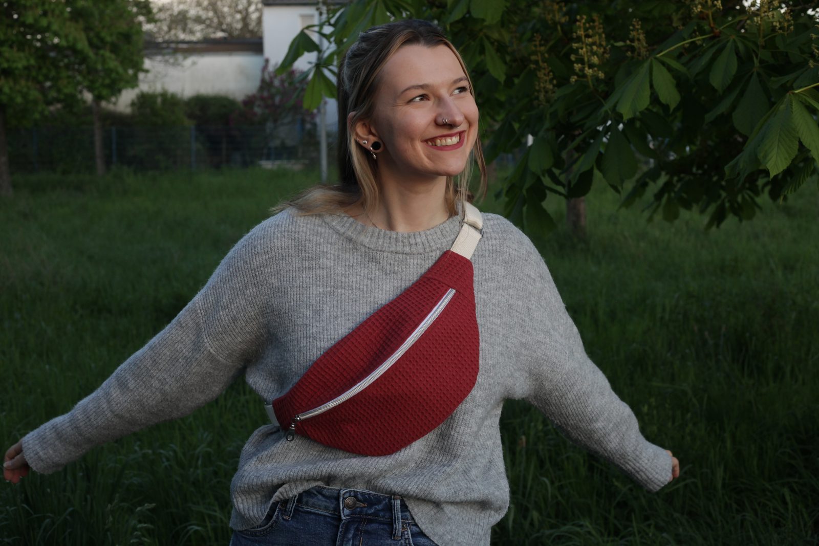 Dunkelroter Koala quer über einem grauen Strickpullover, im Garten