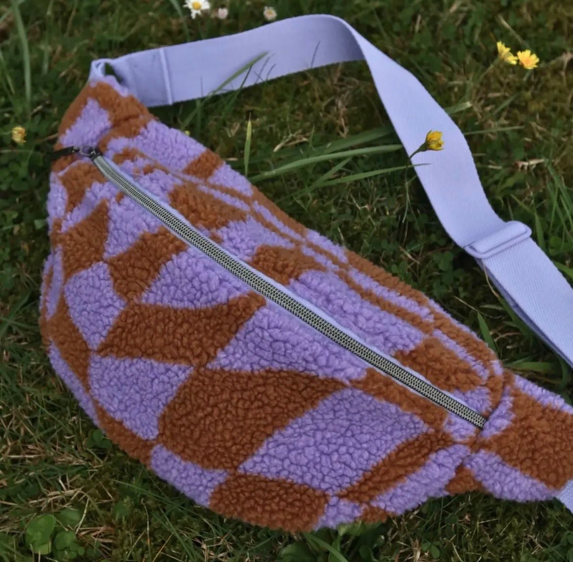 Koala aus lila-rostfarbenem Teddy-Schachbrettstoff, im Gras liegend