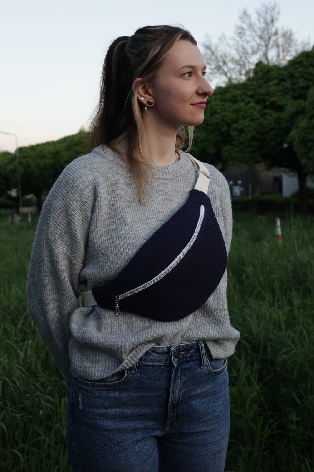 Dunkelblauer Koala quer über einem grauen Pullover, in der Dämmerung